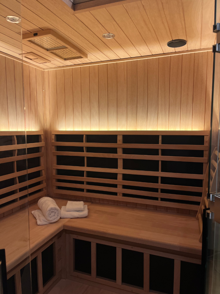 Interior of the private cedar infrared sauna at Allure with far-infrared panels, bench seating and fresh towels