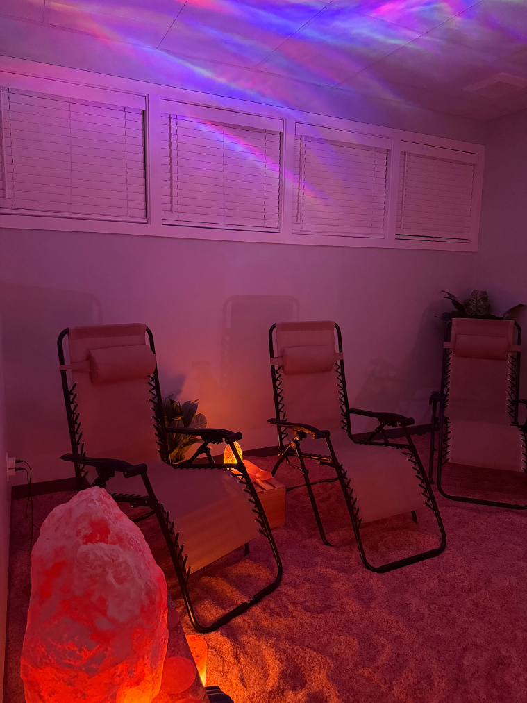 The Salt Spa at Allure &mdash; zero-gravity recliners on a bed of pink Himalayan salt, lit softly with a glowing salt lamp and gentle blue light